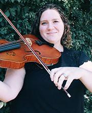 Dr. Cassie Sulbaran smiling with medium length brown wavy hair wearing a black short sleeve top and playing a violin