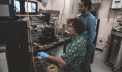 Dr. Samuel Serna and Brahmin Thurber-Carbone work in a lab a