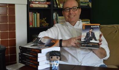Arthur lizzie教授拿着他最近出版的关于音乐家Prince的书