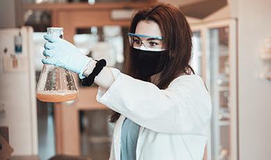 Ashlyn Grace Kelly holds a beaker while working in a lab.