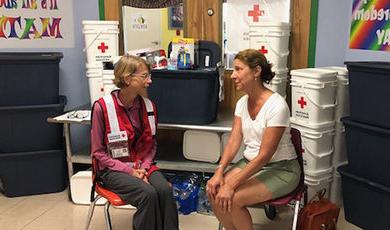 穿着红十字会背心的玛吉·洛与一名洪水灾民交谈.