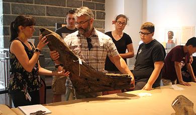 卡尔文·米雷斯把一根木料从“麻雀鹰”上搬到桌子上.