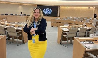 Tiana wears a yellow skirt standing in the assembly room in the United Nations in Geneva 